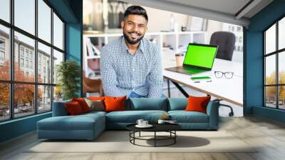 Indian businessman working on laptop indoors in modern office Wall mural